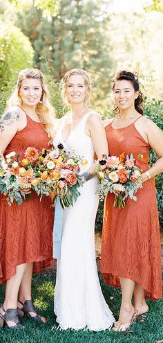 three bridesmaids in orange dresses holding bouquets