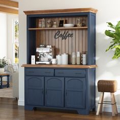 a coffee bar with blue cabinets and wooden floors in a living room area, next to a potted plant