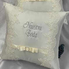 two white pillows with embroidered words and bows on the sides, one is made out of satin