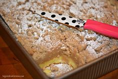 a pink and black polka dot knife sitting on top of a pan filled with powdered sugar