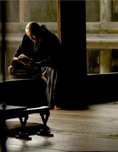 an old man sitting on a bench reading a book in the middle of a room