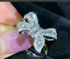 someone is holding a diamond bow ring in their hand