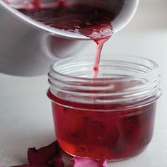 a person pouring red liquid into a jar