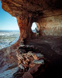 a person climbing up the side of a mountain with a rock formation in front of them