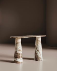 two marble pedestals stand next to each other in front of a brown wall and floor