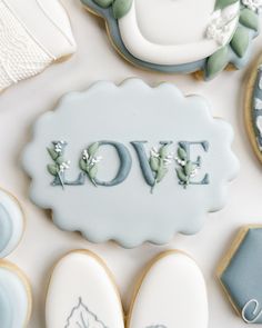 decorated cookies with the word love spelled in cursive writing on them, surrounded by other cookie decorations