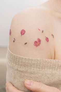 a woman's shoulder with pink flowers on her left shoulder and the upper half of her arm