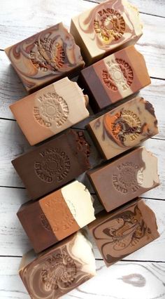 several different types of soaps are arranged on a white wooden surface, one is brown and the other is orange