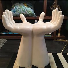 a white sculpture with two hands on top of it