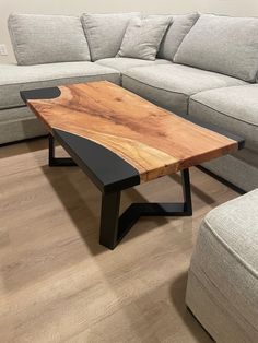 a wooden table sitting on top of a hard wood floor next to a gray couch