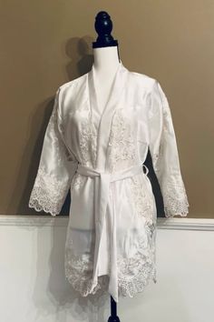 a white robe on a mannequin with lace trims and an open collar