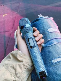 a person holding a microphone in their left hand and an old pair of jeans on the other