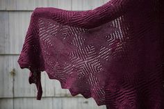 a purple knitted shawl hanging from a clothes line