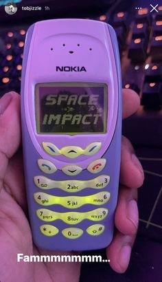 a person holding a purple nokia cell phone in their hand with the words space impact on it