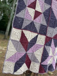 a crocheted blanket hanging from a tree