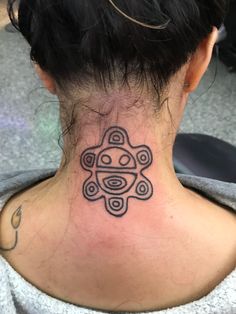 the back of a woman's neck with a tattoo design on her left side