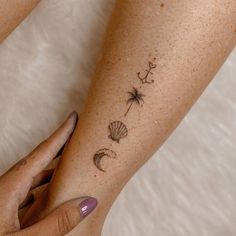 a woman's arm with tattoos on it and a starfish, seashells, and an umbrella