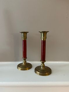 two red candlesticks sitting on top of a white shelf