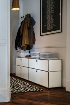 a white dresser sitting next to a black and white rug on top of a hard wood floor