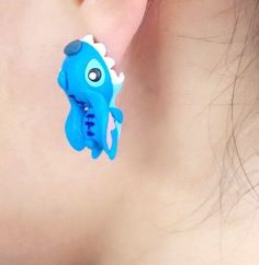 a close up of a person's ear wearing blue and white earrings with an elephant on it