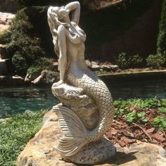 a statue of a mermaid sitting on top of a rock