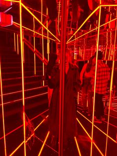 people are standing in a room with red and yellow lines on the walls, while one person is taking a photo