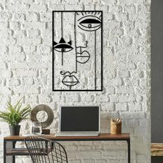 a white brick wall with a black and white drawing on it's face next to a computer desk