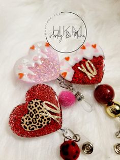 three heart shaped keychains with different designs and colors are on a white fur surface