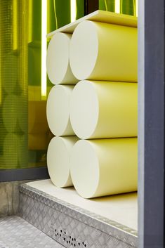 yellow and green vases are stacked on top of each other in front of a window