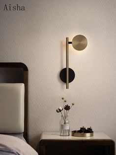 a white bed sitting next to a wall mounted lamp