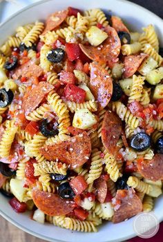 a bowl filled with pasta salad on top of a wooden table