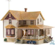 a toy house with a porch and two stories on the front, sitting in front of a white background