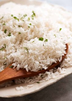 white rice in a bowl with a wooden spoon