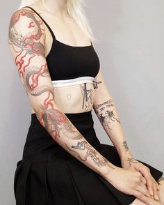 a woman with tattoos on her arm sitting down