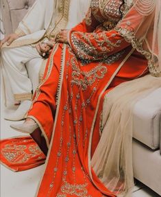 a man and woman sitting next to each other on a couch wearing wedding attires