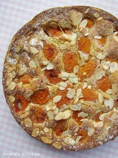 a pie with almonds and other toppings sitting on a checkered table cloth