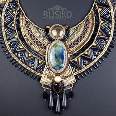 an elaborate necklace with blue and gold beads on it's sides, hanging from a black background