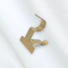 a pair of gold ear clips sitting on top of a white sheet