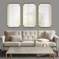 a living room with three mirrors on the wall and a couch in front of it