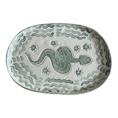 a green and white plate with an animal on it's side, in the shape of a snake