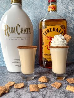 a bottle of rumchata next to two glasses filled with whipped cream and crackers