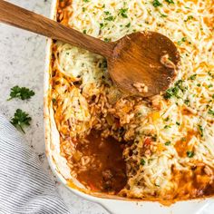 a casserole dish filled with rice, meat and cheese topped with parsley