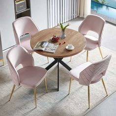 a round table with pink chairs and a magazine on the table in front of it