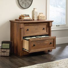 a wooden dresser with two drawers and a clock on the wall