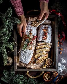 a tray filled with different types of pastries on top of a table next to pine branches