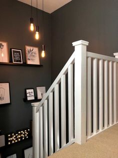 there is a white railing on the stairs in this room with black walls and pictures above it