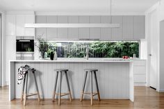 three stools are in front of the kitchen counter and bar with an open window