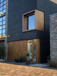 a black brick building with two windows and some potted plants