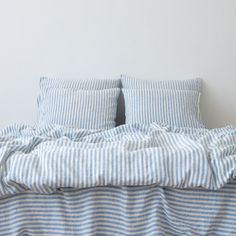 an unmade bed with blue and white striped sheets