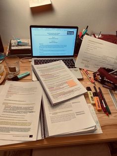 a laptop computer sitting on top of a wooden desk next to papers and pencils